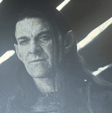 a man with long hair is looking at the camera with a serious look on his face