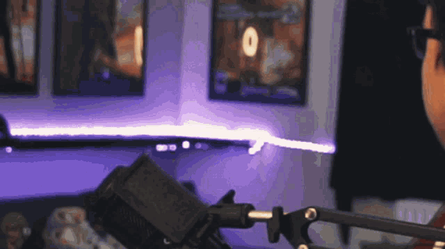 a man is sitting in front of a microphone with a purple light behind him