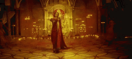 a woman in a red dress is dancing on a stage in a room with candles .