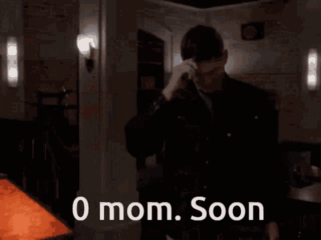 a man in a suit is standing in front of a lamp with the words 0 mom soon written on it