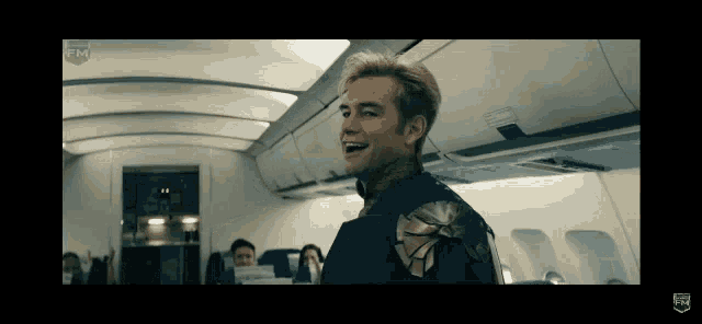 a man in a superhero costume is laughing on an airplane