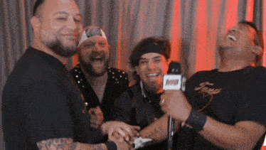 a group of men are laughing and one has a tattoo on his arm that says av