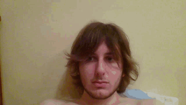 a shirtless man with long hair and a beard is looking at the camera