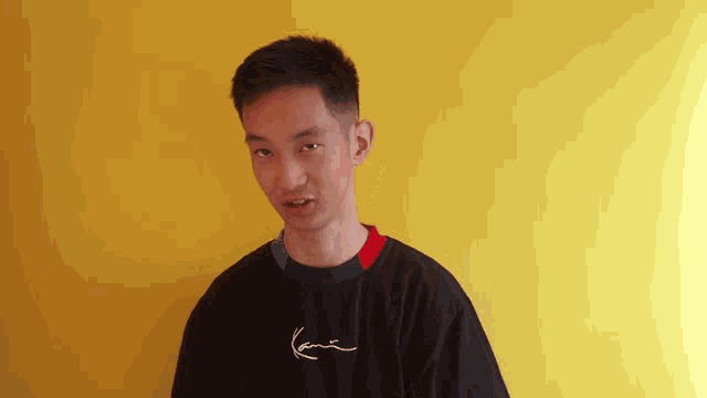 a young man wearing a black karl kani shirt
