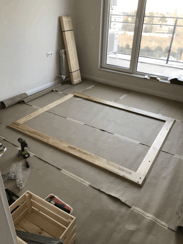 a wooden frame is being built in a room with a drill on the floor