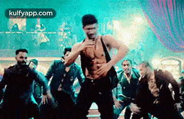 a man without a shirt is dancing in front of a crowd of people .