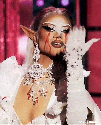 a drag queen is wearing a white dress and white gloves and has blood running down her face .