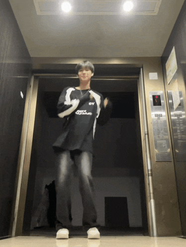 a person standing in an elevator wearing a black shirt that says ' sss ' on it