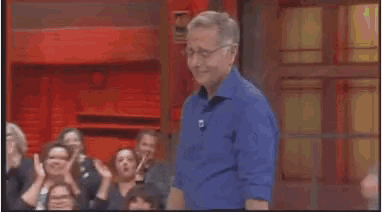 a man in a blue shirt shakes hands with another man in front of a crowd