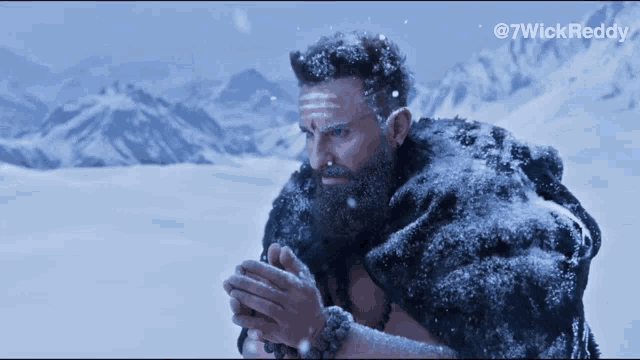 a man with a beard and a fur coat is standing in the snow with mountains in the background