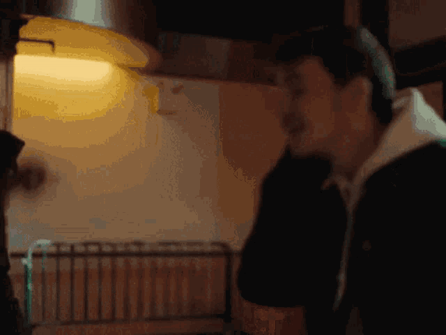 a man in a black jacket is talking to another man with a coca cola bottle in front of him