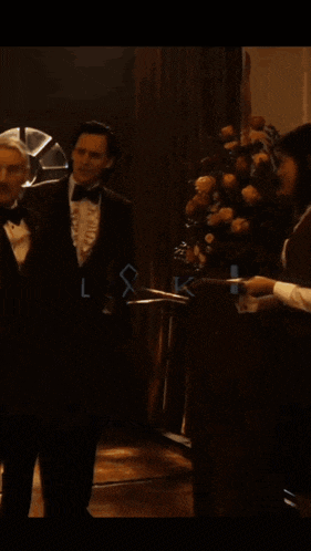a man in a tuxedo is standing next to another man with the words " i can fix that " on the screen