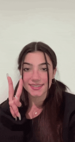 the girl is wearing braces on her teeth and making a peace sign .