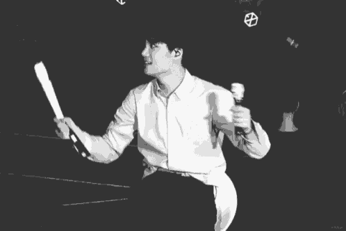 a black and white photo of a man holding a microphone and dancing .