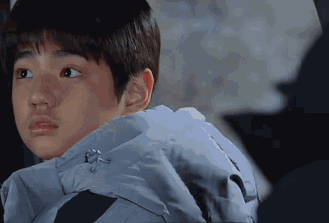 a young boy wearing a blue jacket is looking at something