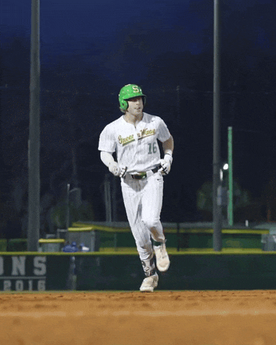 a baseball player wearing a green helmet and a white jersey that says ' greenies ' on it