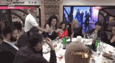a group of people are sitting around a table with a bottle of paparazzi wine on it