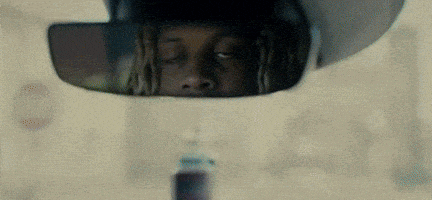 a man is looking at himself in a rear view mirror .