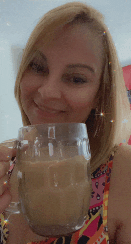 a woman holding a glass of coffee and smiling