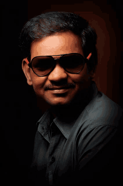 a man wearing sunglasses and a black shirt is smiling for the camera