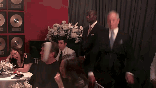 a man in a suit stands in front of a group of people sitting at a table