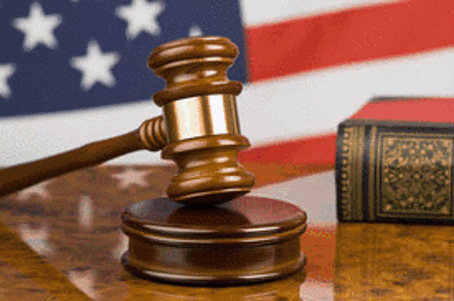 a judge 's gavel sits on a wooden table in front of an american flag