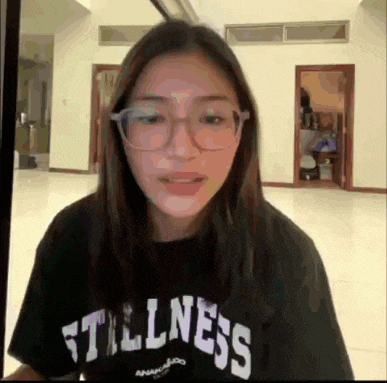 a woman wearing glasses and a black t-shirt that says stillness
