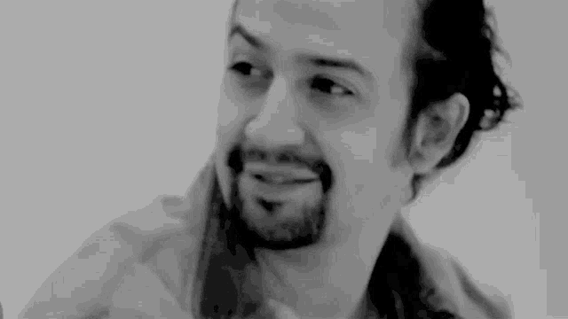 a black and white photo of a man with a beard .