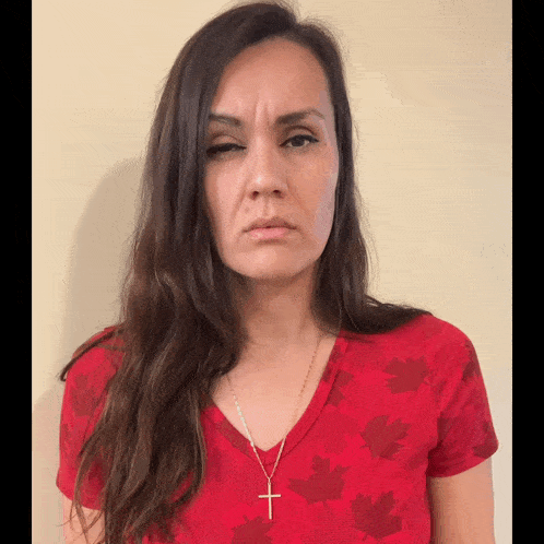 a woman wearing a red shirt with maple leaves and a gold cross necklace