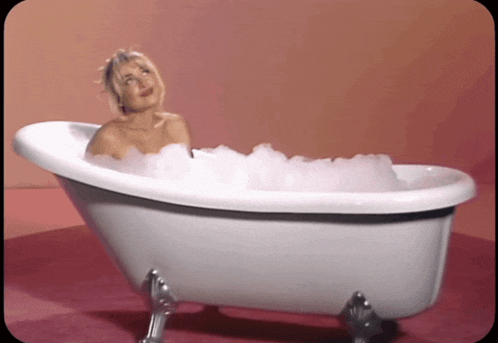 a woman is taking a bath in a tub filled with bubbles