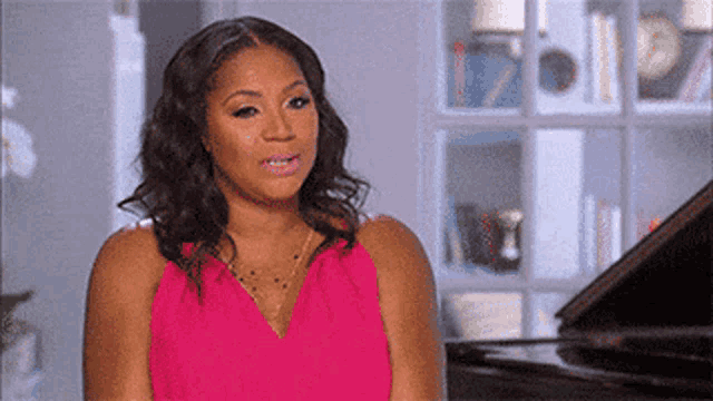 a woman in a pink dress is sitting next to a piano .