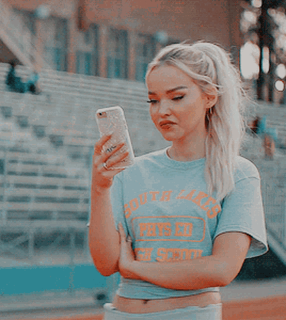 a girl wearing a blue shirt that says south lakes holds a cell phone