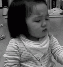 a black and white photo of a little girl wearing a striped shirt and a bib .