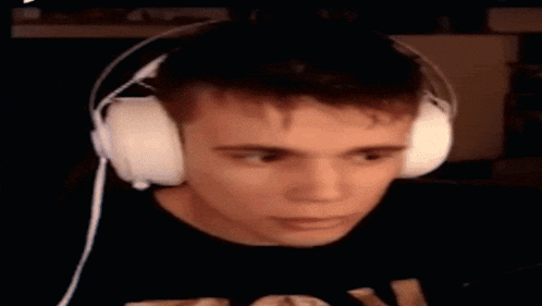 a young man wearing headphones is sitting in front of a computer screen .