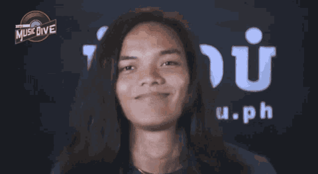 a young man with long hair is smiling in front of a music dive logo