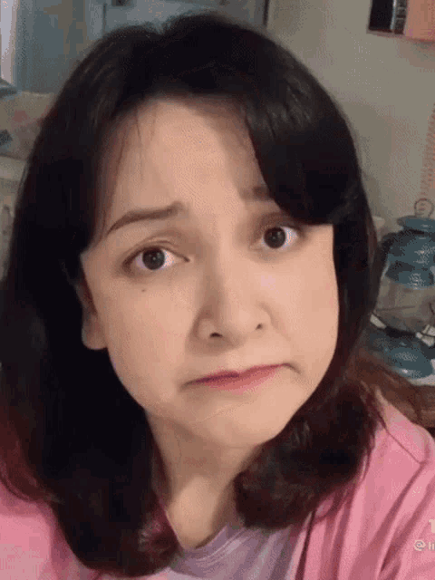 a woman in a pink shirt is making a face .