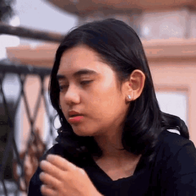 a young woman is sitting on a balcony smoking a cigarette and looking at the camera .
