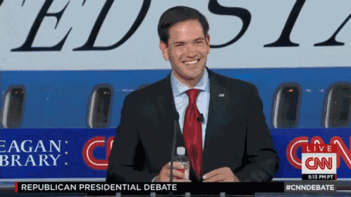 a man in a suit and tie is smiling in front of a cnn banner