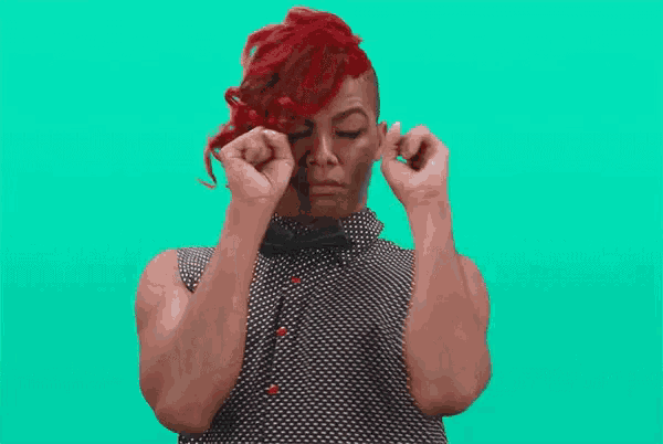 a woman with red hair is flexing her muscles while wearing a polka dot shirt .
