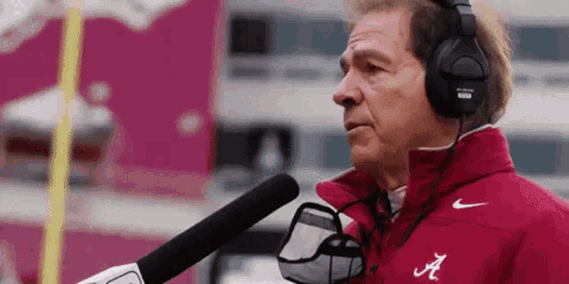 a man wearing headphones and a jacket with the letter a on it is talking into a microphone