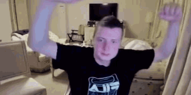 a man in a black shirt is standing in a room with his arms up in the air .