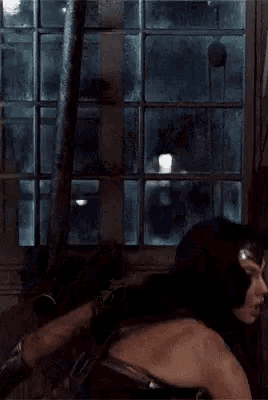 wonder woman is standing in front of a window in a room .