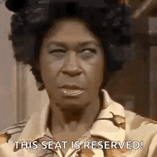 a woman with curlers in her hair is making a funny face and saying `` this seat is reserved '' .