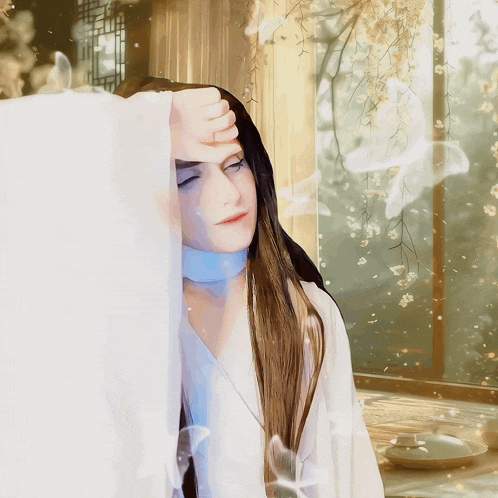 a woman with long hair holds her hand to her forehead in front of a window