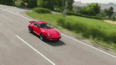 a red porsche is driving down a road with a no entry sign in the background