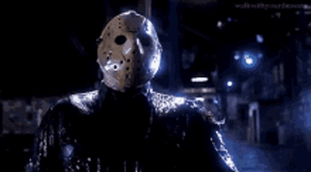 a close up of a person wearing a jason voorhees mask with a light coming out of his eyes .