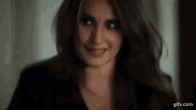 a woman is smiling and looking at the camera while wearing a black jacket .