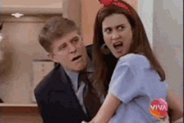 a man and a woman are standing next to each other and the woman is making a funny face .