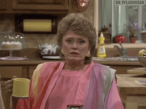 a woman in a pink dress is sitting in a kitchen with a bottle of coca cola