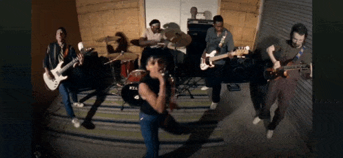 a group of people are playing instruments in a room with a tama drum set in the background
